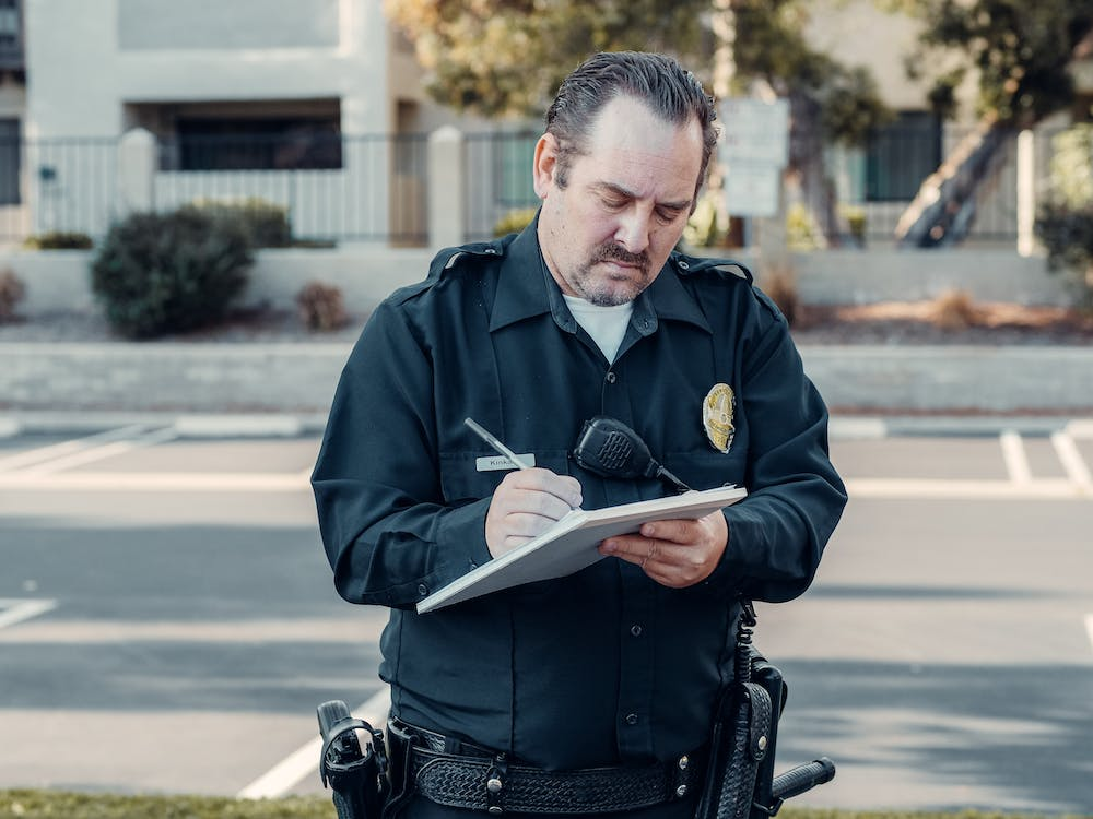 A security professional writing details on a notebook 