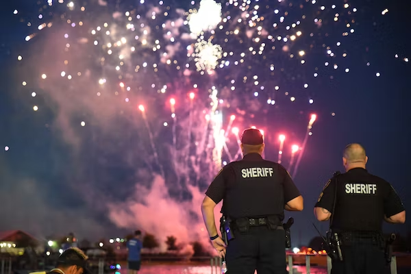 A security guard watching a street with fireworks in the sky