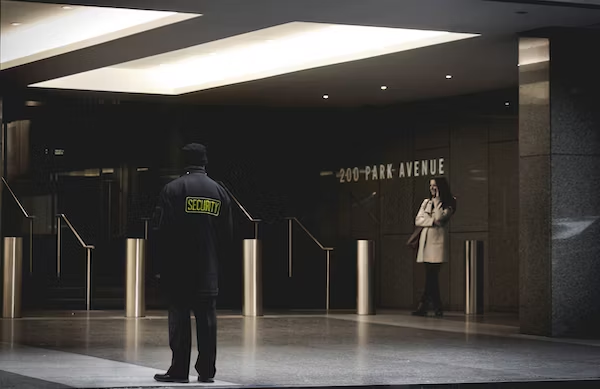 a security guard standing in front of the stairs monitoring the hall at the 200 park avenue building